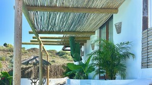 A poolside area with a wooden pergola, lounge chairs, and a view of a pool and greenery. - Boho Villa in Firgas | Pool, Nature, BBQ, and Ocean Views (CN)