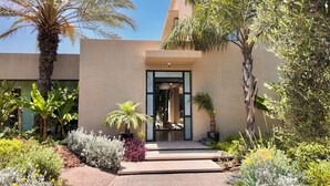 A modern building with a glass entrance, surrounded by various plants and a paved pathway. - Villa Loulou, heated pool and breakfast included (Marrakech)
