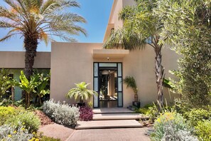 A modern building with a glass entrance, surrounded by various plants and a paved pathway. - Villa Loulou, heated pool and breakfast included (Marrakech)