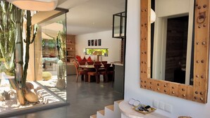 A modern interior with a dining area, a staircase, and a large mirror. - Villa Loulou, heated pool and breakfast included (Marrakech)