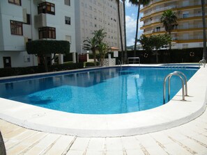 A swimming pool with a metal ladder, surrounded by a white tiled deck. - Apartment sea view, AC and parking - 6 guests (Gandia)
