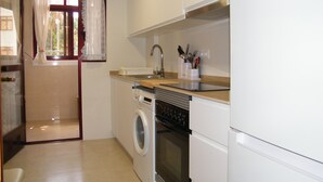 Eine kleine Küche mit Waschmaschine, Backofen und Spüle inklusive Geschirr.