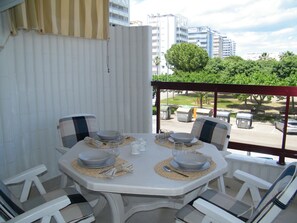 A dining area with a table set for four, outdoor chairs, and a view of a cityscape with buildings and trees. - Apartment sea view, AC and parking - 6 guests (Gandia)