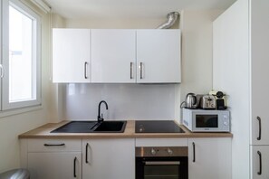 Eine kleine Küche mit weißen Schränken, einer schwarzen Spüle, einer Mikrowelle und einem Toaster.