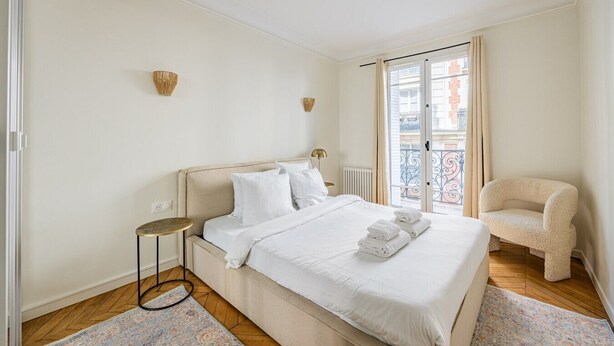 Une chambre d’hôtel avec un lit, une chaise, une petite table et une vue sur l’extérieur.