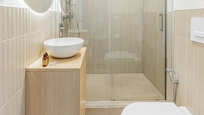 Une salle de bain moderne dotée d’une douche à parois de verre, de toilettes sur pied et d’un meuble-lavabo avec un évier.