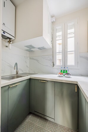 A kitchen with a sink, cabinets, and a window. - Arc de Triomphe - Bail Mobilité - Place Victor Hugo - 2-bedroom (Paris)