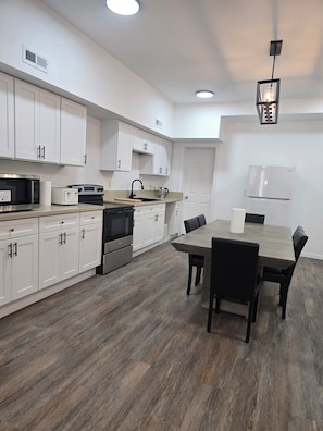 A modern kitchen with white cabinets, a dining table, and a built-in oven. - Spacious 6-bedroom building with AC in serene Cincinnati (Cincinnati)