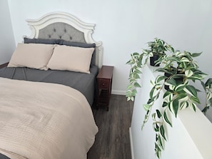A bedroom with a bed, a nightstand, a dresser, and a potted plant. - Spacious 6-bedroom building with AC in serene Cincinnati (Cincinnati)
