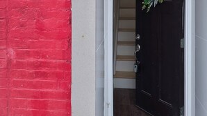 Entrada de un edificio con una puerta negra, una placa blanca con el número '2035' y un adorno navideño verde colgado en la puerta.