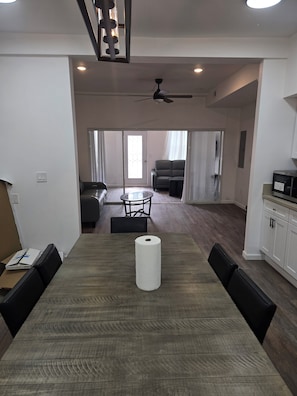 A dining area with a table, chairs, a ceiling fan, and a view to a living room with a sofa and a TV. - Spacious 6-bedroom building with AC in serene Cincinnati (Cincinnati)