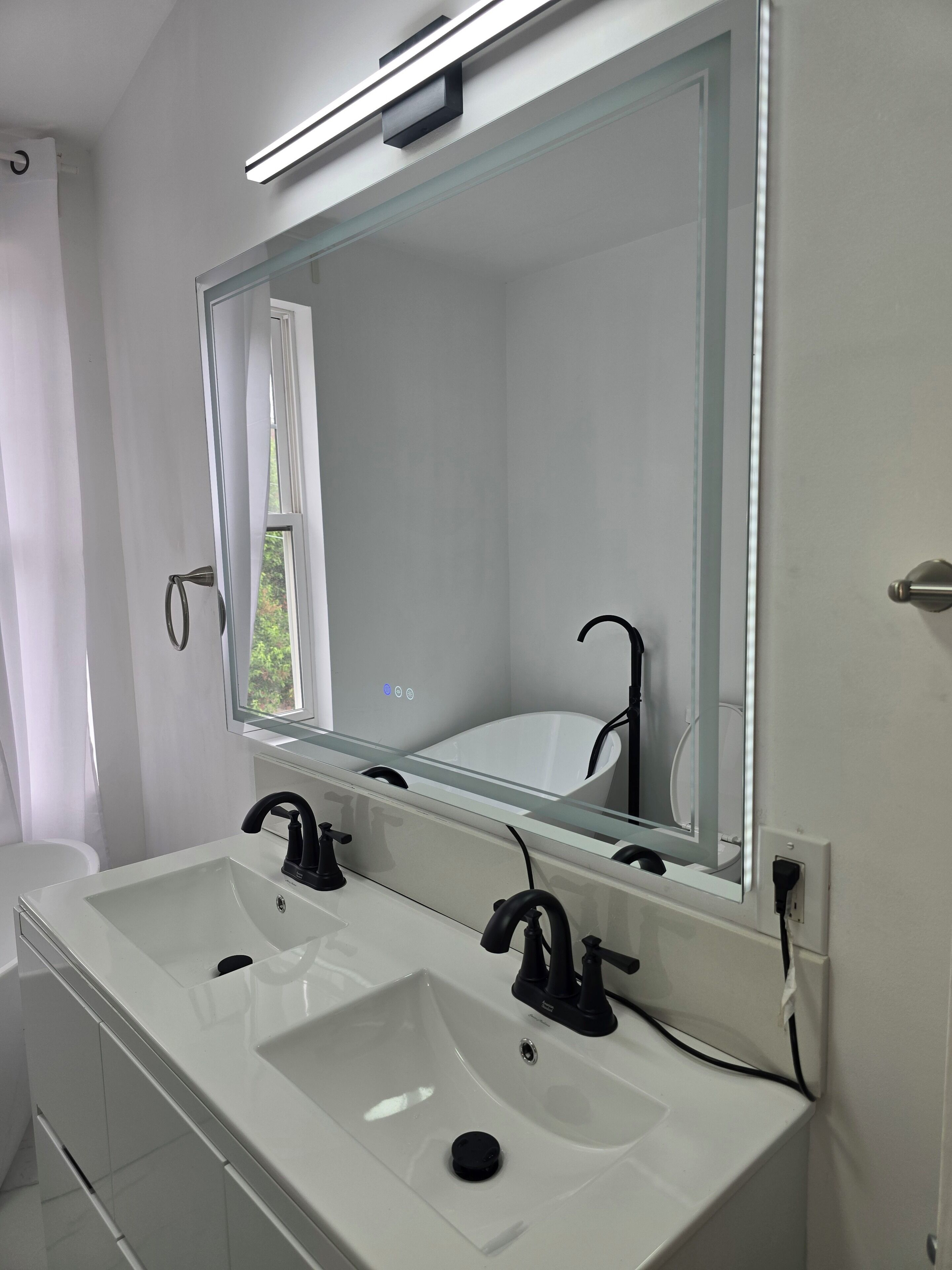 A modern bathroom with two sinks, a large mirror, and a window.