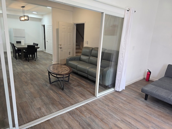 A modern living room with a grey sofa, a round coffee table, and a dining area with a white table and chairs. - Spacious 6-bedroom building with AC in serene Cincinnati (Cincinnati)