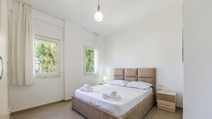 Et rent, moderne værelse med en træseng, to sengeborde og et vindue med gardiner.