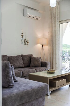Ein modernes Wohnzimmer mit Sofa, Couchtisch, Lampe und Blick ins Freie.