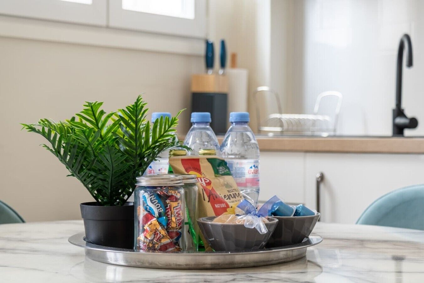 Een keukenblad met een bloempot, een blik voedsel, flessen water en een kom met een plastic zak.