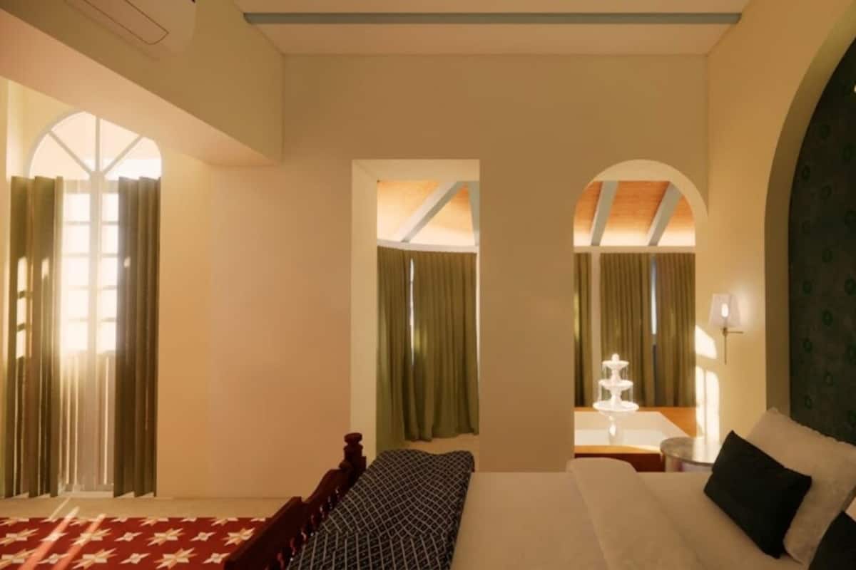 A hotel room with a bed, a sofa, a desk, and a mirror.