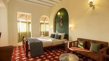 A hotel room with a bed, a sofa, a round table, and a wall-mounted lamp.