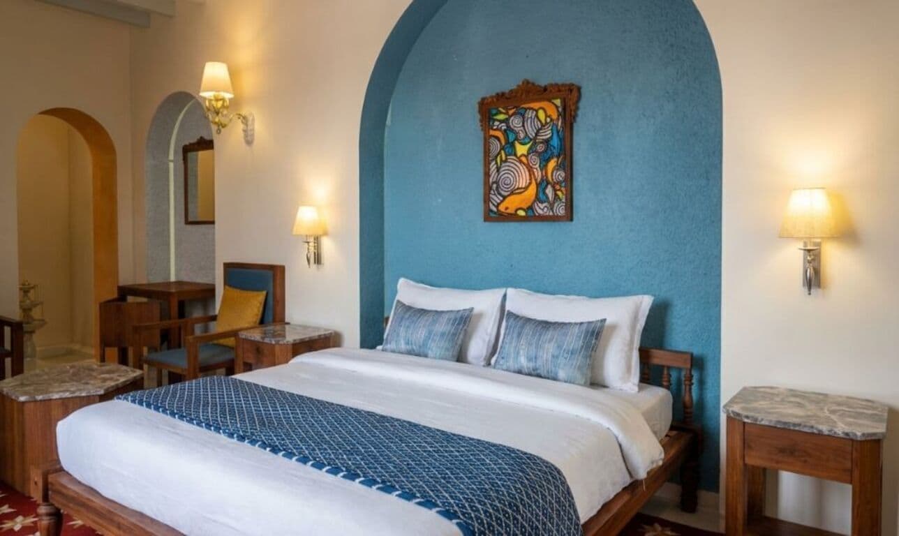 A hotel room with a large bed, two bedside tables, a chair, a desk, and a wall-mounted artwork.