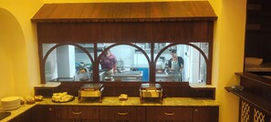 Una cocina con un gran ventanal, armarios de madera y una encimera con alimentos.