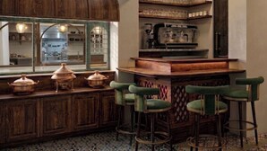 Een bar met krukken, een houten toonbank en uitzicht op de keuken.