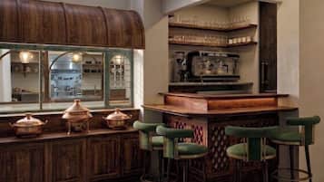 A bar area with stools, a wooden counter, and a view into the kitchen.