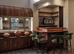Zona de bar con taburetes, una barra de madera y vistas a la cocina.