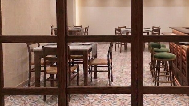 A dining area with tables and chairs, a patterned floor, and a wooden partition. - La Maison Pondichéry (Puducherry)