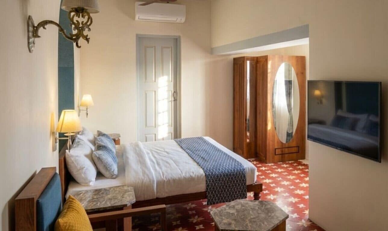 Une chambre d’hôtel comprenant un lit, une table de chevet, une lampe, une armoire et un téléviseur.