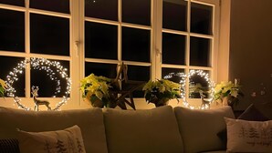 Una sala de estar acogedora con un sofá, una manta escocesa roja y luces decorativas.