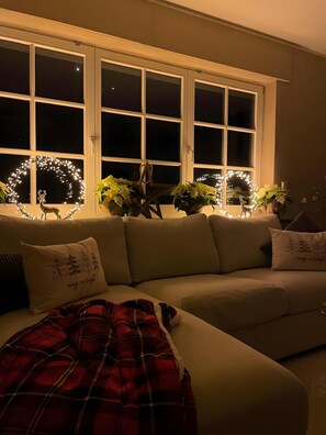 Ein gemütliches Wohnzimmer mit einer Couch, einer roten Karo-Decke und dekorativer Beleuchtung.