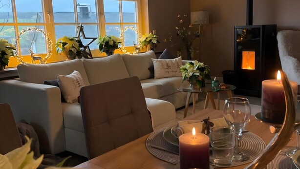 Una sala de estar acogedora con sofá, mesa de comedor dispuesta con velas y chimenea.