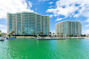 Ein Hotel am Wasserufer mit mehreren Balkonen, einer Marina und wolkenlosem Himmel.