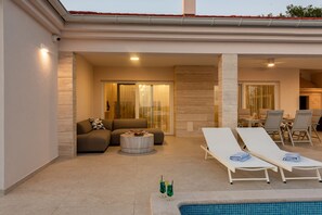 Ein Poolbereich mit Liegestühlen, einer Sitzecke und einem Esstisch.