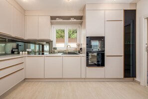 Eine moderne Küche mit weißen Schränken, einem eingebauten Ofen und einem Fenster über der Spüle.