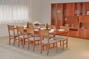 A dining area with a wooden table and chairs, a vase with flowers, and a cabinet with glassware. - Unwind among the pine trees and by the sea in Begur. House 5 minutes from Sa Riera Beach (Sa Riera)