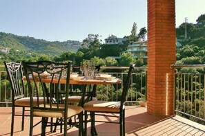 A terrace with a table and chairs, a brick pillar, and a view of a green hillside with buildings in the background. - Unwind among the pine trees and by the sea in Begur. House 5 minutes from Sa Riera Beach (Sa Riera)