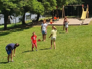 Ein parkähnliches Grünanlage mit Spielplatz, einschließlich Schaukeln und Rutsche.