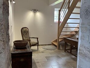 A staircase with wooden steps and a handrail, a chair with a woven basket, and a wall-mounted light fixture.