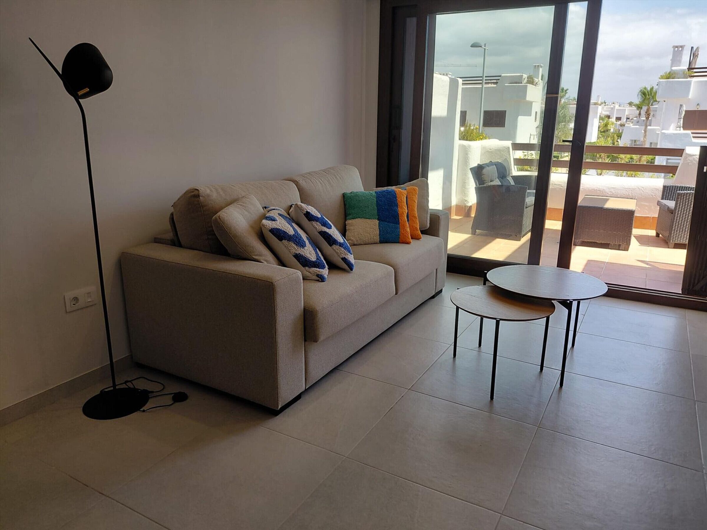 A modern living room with a sofa, a small round table, and a floor lamp.