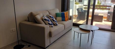 A modern living room with a sofa, a small round table, and a floor lamp.