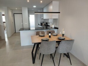 A modern kitchen with a central island, dining table, and chairs. - Modern apartment, sea view - 4 guests (San Juan de los Terreros)