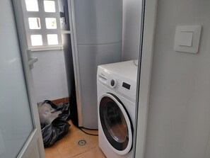 A compact laundry room with a front-loading washing machine, a dryer, and a window with a grid pattern. - Modern apartment, sea view - 4 guests (San Juan de los Terreros)