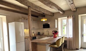 A kitchen with wooden beams, a white refrigerator, a sink, a wooden countertop, and a window with curtains. - Stone house with parking - 4 guests (Blis-et-Born)
