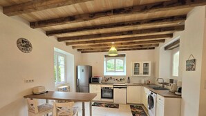 A kitchen with wooden beams, a dining table, a refrigerator, a microwave, an oven, and a washing machine. - Idyllic home, pets and parking - 6 guests (Saint-Vincent-Jalmoutiers)