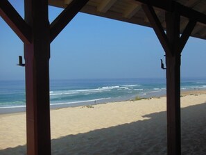 Blick auf einen Strand von einer Holzkonstruktion bei blauem Himmel.