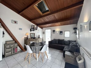A cozy loft-style living space with a dining area, a sofa, and a television mounted on the wall. - Quiet house, heated pool - 5 guests (Bretignolles-sur-Mer)