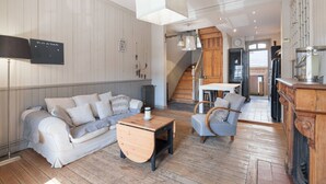 Ein modernes Wohnzimmer mit einer Couch, Sesseln, einem Couchtisch und einer Treppe, die in ein Obergeschoss führt.