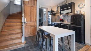 Eine Küche mit einer Holztreppe, einem weißen Tisch und einem schwarzen Kühlschrank.