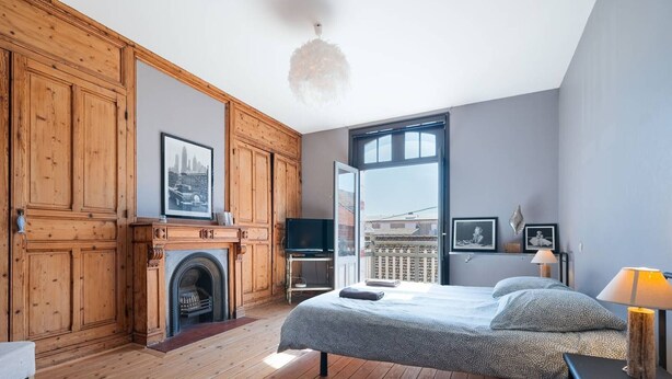Ein Schlafzimmer mit Bett, Fernseher, Kamin und einem Balkon mit Blick.